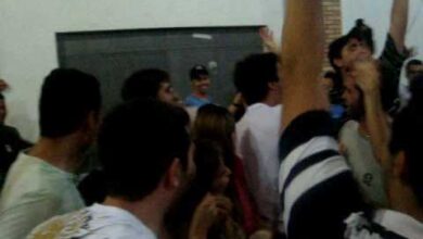 Estudantes em um churrasco universitário entoando um hino polêmico, típico de festas universitárias